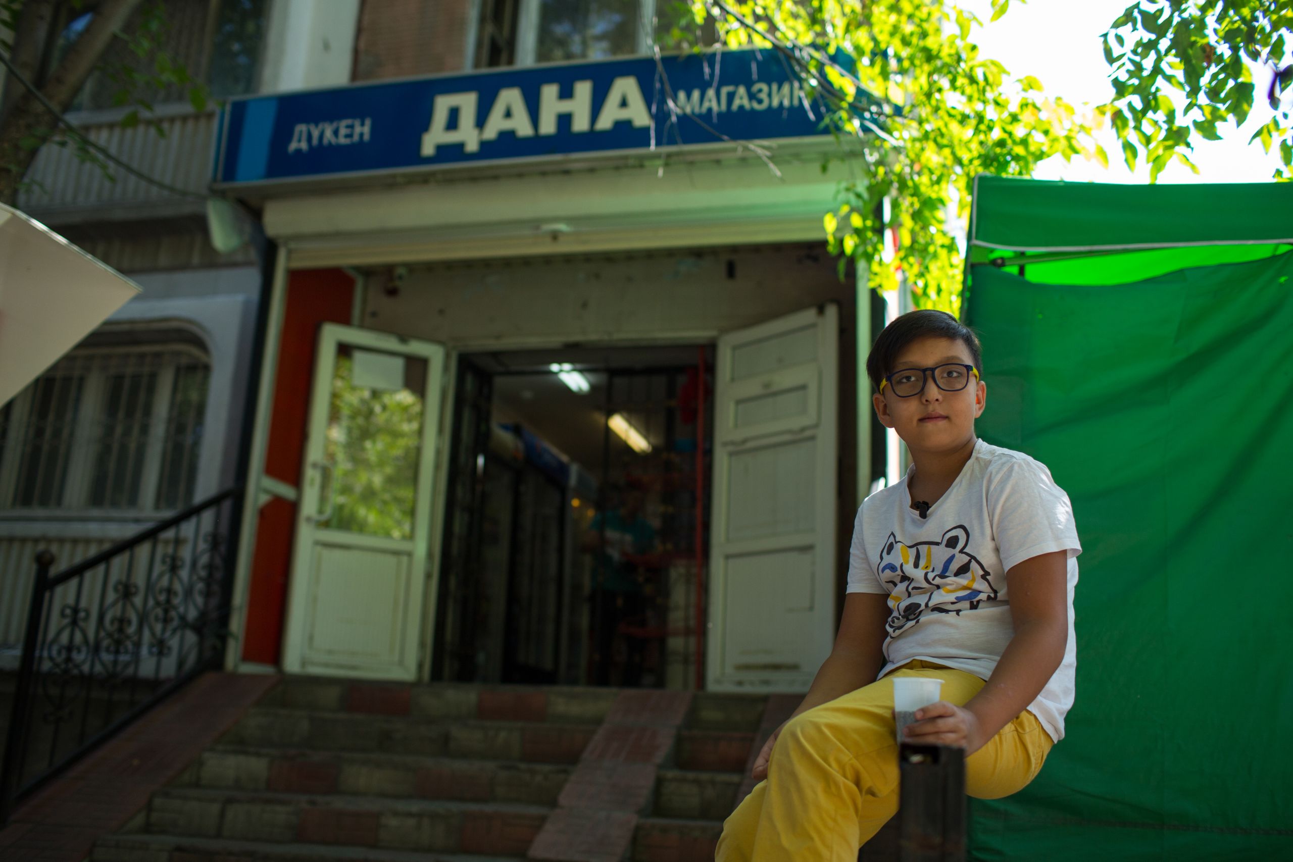 Un enfant est assis devant une épicerie, Kazakhstan